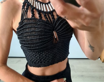May include: A black crocheted halter top with a silver beaded neckline. The top is cropped and has a fitted silhouette.