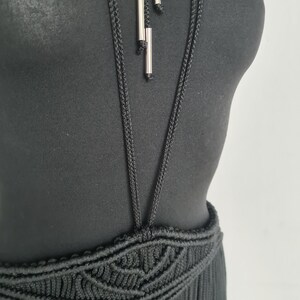May include: A black halter top with a crocheted skirt. The top has a long, thin, black cord with silver accents hanging from it.