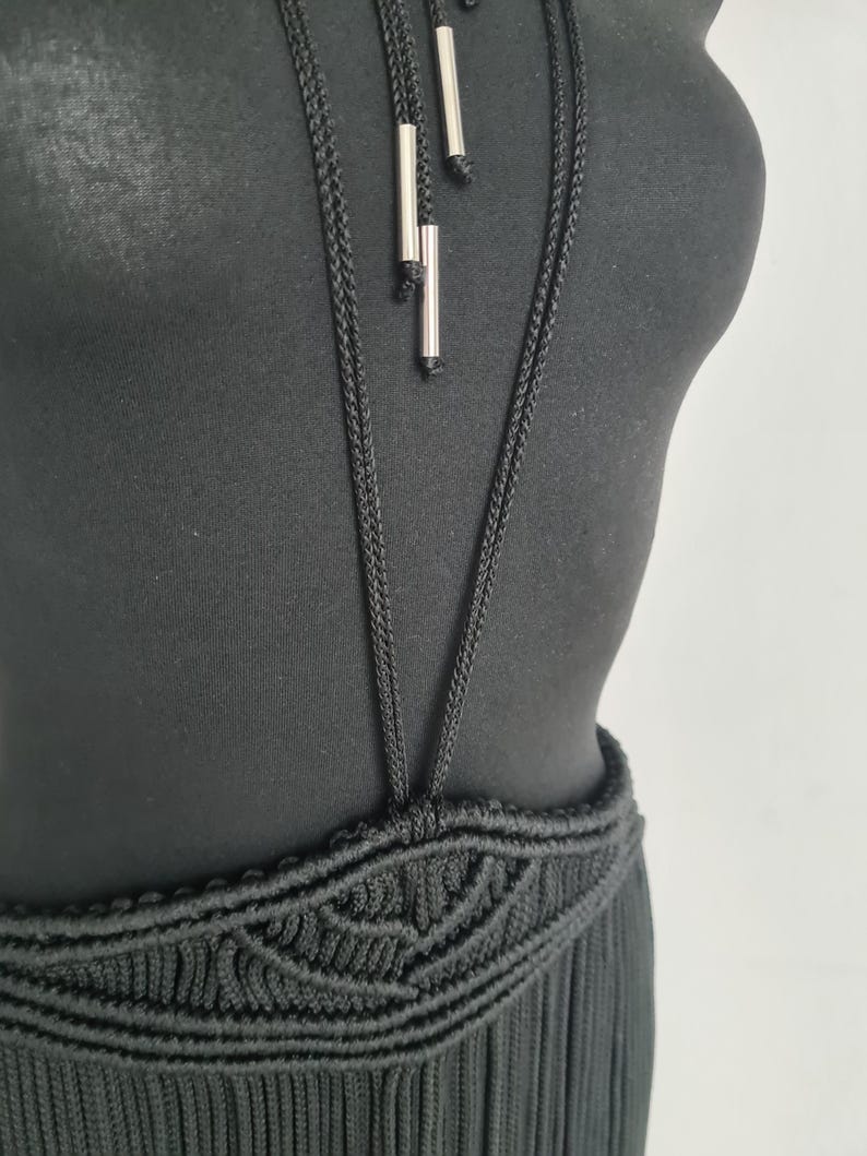 May include: A black halter top with a crocheted skirt. The top has a long, thin, black cord with silver accents hanging from it.