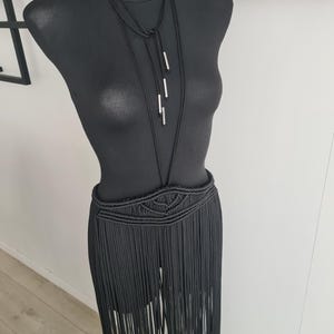 Black long macramé skirt connected to a neck accessory with metallic details, showcasing intricate handmade patterns and a bold, elegant design, perfect for special occasions or festivals.