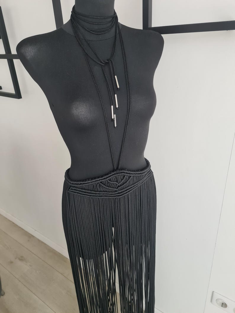 Black long macramé skirt connected to a neck accessory with metallic details, showcasing intricate handmade patterns and a bold, elegant design, perfect for special occasions or festivals.
