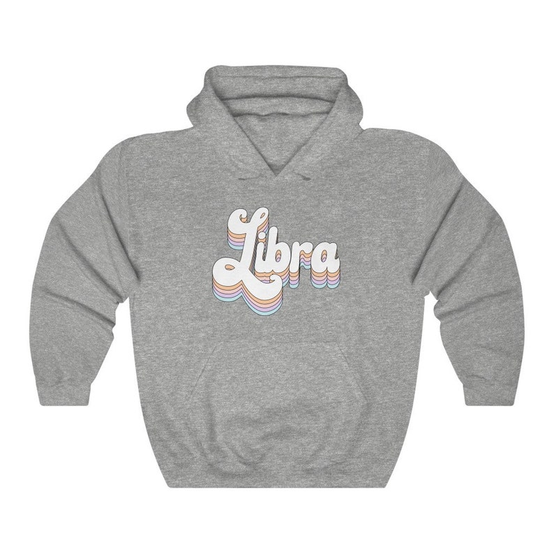 K&ouml;nnte beinhalten: Ein grauer Kapuzenpullover mit dem Wort "Libra" in einer retro-Regenbogen-Schrift auf der Vorderseite.