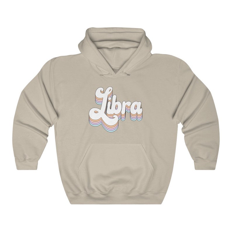 K&ouml;nnte beinhalten: Ein hellbeiger Hoodie mit einem wei&szlig;en Retro-&bdquo;Libra&ldquo;-Motiv in Regenbogenfarben.