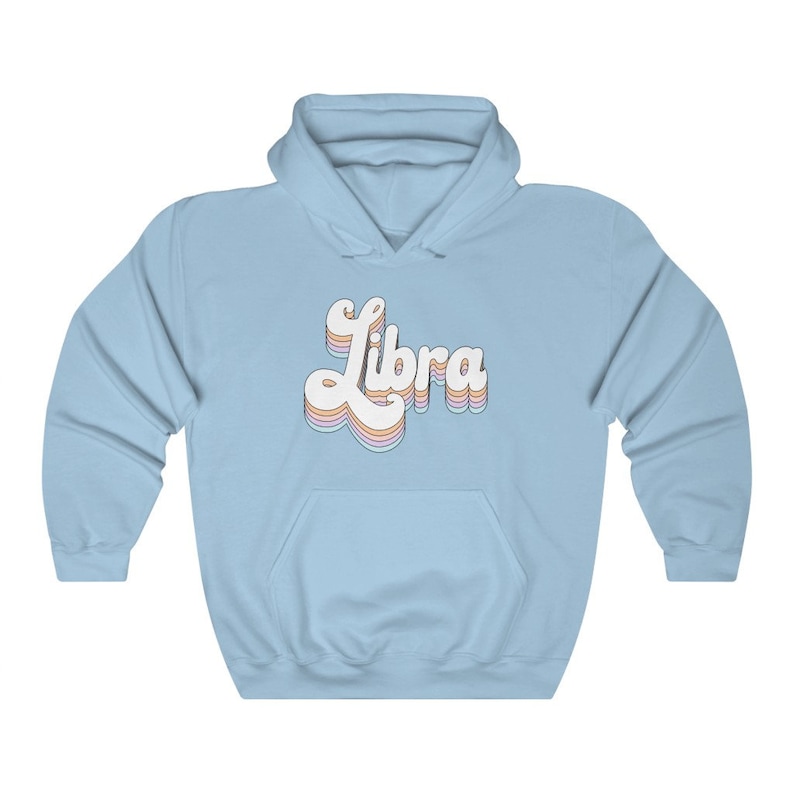 K&ouml;nnte beinhalten: Hellblauer Kapuzenpullover mit dem Wort "Libra" in einer Retro-Schriftart in Regenbogenfarben.