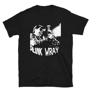 Puede incluir: Camiseta gráfica en blanco y negro con la silueta de Link Wray tocando la guitarra. El texto "Link Wray" está impreso en blanco debajo de la imagen.