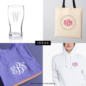 May include: A set of three different items featuring a monogram design with a wreath of leaves. The items include a glass beer mug, a tote bag, and a t-shirt. The monogram is in a cursive font and is in pink.