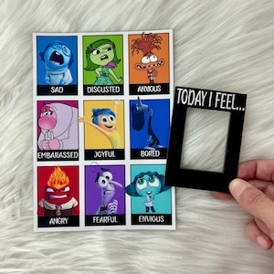 Può includere: Una stampa quadrata con personaggi dei cartoni animati che rappresentano emozioni come "Triste", "Disgustato" e "Ansioso". Una cornice nera con la scritta "TODAY I FEEL..." è accanto alla stampa.
