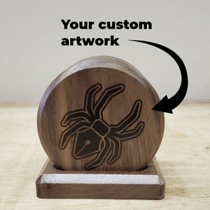 May include: Set of four wooden coasters with a black spider design. The coasters are stacked on a wooden stand. "Your custom artwork" is written above the coasters.