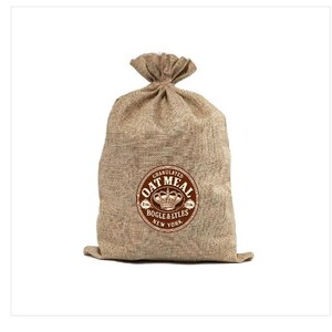 May include: A tan burlap sack with a drawstring top closure. Centered on the front is a circular brown graphic featuring a crown icon and the text: GRANULATED OAT MEAL, BOGLE & LYLES, NEW YORK, with the numbers 2116 on either side of the crown.