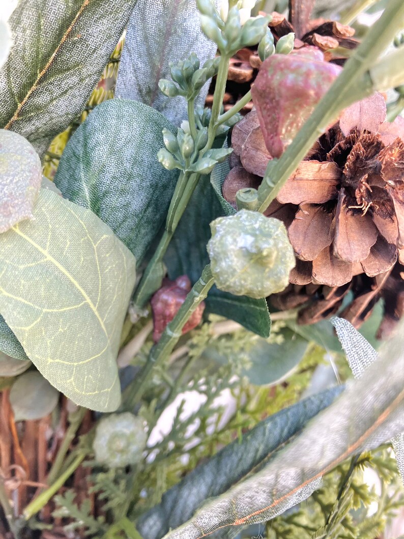 Op de afbeelding: Een close-up van een kunstbloemenarrangement met dennenappels, eucalyptusbladeren en ander groen. De opstelling is perfect om elke ruimte een vleugje natuur te geven.