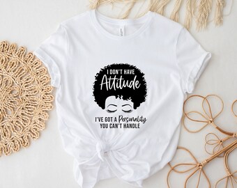 Peut inclure: T-shirt blanc avec une silhouette noire d'une femme avec des cheveux crépus et le texte "I don't have attitude I've got a personality you can't handle."