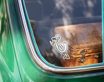 May include: A white goose sticker with a black beret and a speech bubble that says "Le Honk" is on the back window of a green car. The goose is holding a cigarette in its beak.