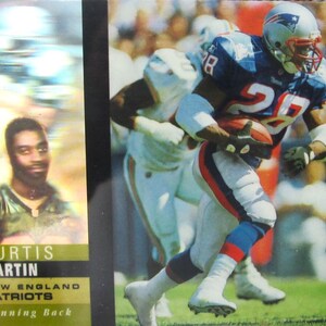 Puede incluir: Una taza de cerámica blanca con un asa negra y el texto "But First, Coffee" en negro, con una fuente de estilo manuscrito. La taza está sobre una superficie blanca.