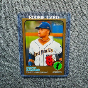May include: A baseball rookie card featuring Jordyn Adams of the Tri-City Dust Devils. The card has a gold border and includes the text "ROOKIE CARD". Adams is wearing a white jersey with "Dust Devils" on the front and a blue cap.