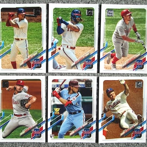 May include: Six baseball trading cards featuring Philadelphia Phillies players. Each card has a white background with a blue, red, and white design. The cards feature photos of the players in their uniforms, with their names and team logos printed on the cards.