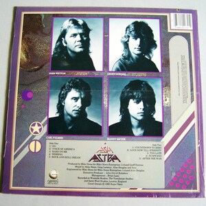 May include: The back cover of the Asia Astra album features four band member portraits in individual boxes. The album title and track listings are visible. The color scheme includes purple, white, and gold accents.