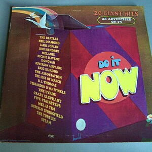 May include: Vintage vinyl record album cover titled "Do It Now" featuring a list of artists including The Beatles, Neil Diamond, and Janis Joplin. The cover has a retro design with the words "Do It Now" in large yellow letters.