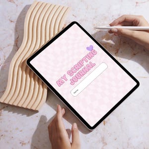 May include: A digital tablet displaying a pink and white checkered design with the text "MY SCRIPTING JOURNAL" and a space for a name. A wooden wave-shaped object and a hand holding a stylus are also visible.