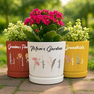 May include: Three ceramic flower pots with personalized text and floral designs. The pots are red, white, and yellow. The text on the pots reads "Grandma's Flowers", "Mom's Garden", and "Grandkids".