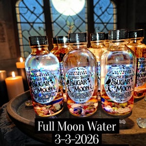 May include: Several glass bottles of "Sugar Moon" full moon water are displayed. Each bottle has a black cap and a label with text and graphics. The bottles are filled with a clear liquid and colorful crystals. The text "Full Moon Water 3-3-2026 Eclipsed Blood Moon" is at the bottom.