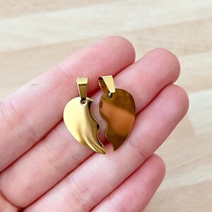 May include: Two gold-coloured metal pendants shaped like halves of a heart. The pendants are designed to fit together to form a whole heart.