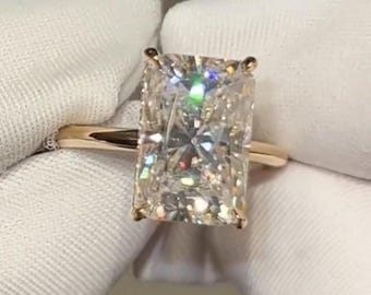 May include: A gold ring with a large, rectangular, clear diamond.
