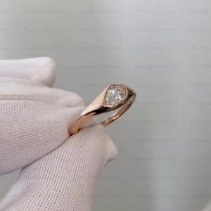 Puede incluir: Un anillo de oro rosa con un diamante en forma de pera. El diamante est&aacute; engastado en un bisel, y la banda es lisa y pulida. El anillo es una pieza de joyer&iacute;a cl&aacute;sica y elegante.