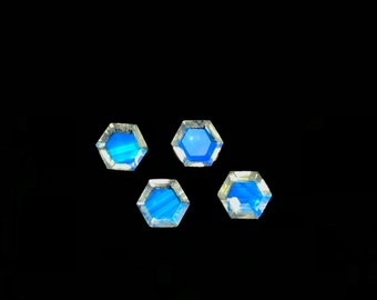 May include: Four hexagonal gemstones with a bright blue interior and a clear, faceted border are displayed against a black background. The gems are arranged in a loose cluster, showcasing their unique shape and color.