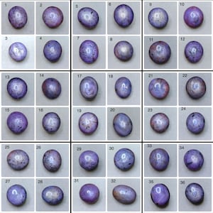 Può includere: Una collezione di trentasei gemme ovali lucide, in tonalità viola, lavanda e grigio. Ogni pietra presenta un motivo e una variazione di colore unici, presentati su uno sfondo neutro. Le gemme sono numerate da 1 a 36.