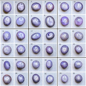May include: A grid of thirty-six oval-shaped, lavender-colored gemstones. Each stone has a unique pattern of internal light and color variations, ranging from pale to deep purple. The stones are arranged in a grid against a white background.