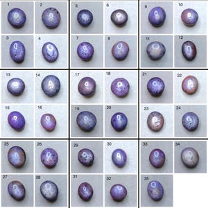 May include: A collection of thirty-five oval gemstones, each within a square frame. The stones range in colour from deep purple to lavender, with some showing star-like patterns. The gemstones are numbered from 1 to 35.