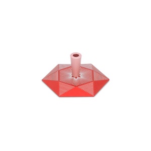 May include: A red and pink geometric candle holder with a white geometric pattern. The holder has a tall, cylindrical centre piece.