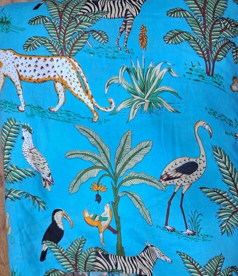 Puede incluir: Una tela de color azul brillante con un patr&oacute;n repetitivo de animales salvajes y plantas tropicales. El estampado incluye un guepardo, cebras, un flamenco, un tuc&aacute;n, una cacat&uacute;a y un p&aacute;jaro peque&ntilde;o, entre palmeras y follaje verde.