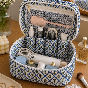 May include: A quilted fabric travel organizer bag featuring a blue and green diamond pattern with small floral motifs. The open case reveals a top mesh zippered pocket, four vertical interior compartments, and a spacious main storage area.