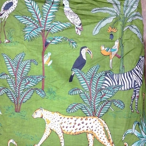 Puede incluir: Una tela verde con un estampado repetitivo de tem&aacute;tica selv&aacute;tica. El dise&ntilde;o incluye un leopardo, una cebra, un tuc&aacute;n, una cacat&uacute;a blanca y un ave de patas largas entre palmeras y follaje tropical, en tonos verdes, blancos, negros y naranjas.