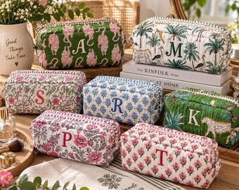 Könnte beinhalten: Eine Sammlung von sechs rechteckigen, gesteppten Taschen mit verschiedenen Blumen- und Tiermotiven, die jeweils mit einem einzelnen Großbuchstaben bestickt sind. Die Taschen zeigen Muster mit grünen Leoparden, Palmen und rosa Blumen sowie Reißverschlüsse.