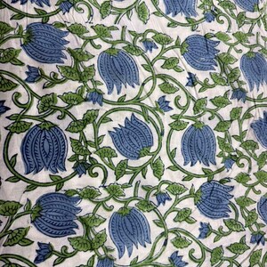 K&ouml;nnte beinhalten: Nahaufnahme eines wei&szlig;en Stoffes mit einem sich wiederholenden Muster aus blauen Bl&uuml;ten und gr&uuml;nen Ranken. Die Bl&uuml;ten sind mit mehreren Bl&uuml;tenbl&auml;ttern detailliert, und die Ranken haben kleine, stilisierte Bl&auml;tter. Das Design ist gleichm&auml;&szlig;ig &uuml;ber den Stoff verteilt.