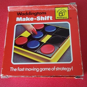 May include: A red box with the words "Waddingtons Make-Shift" and "The fast moving game of strategy!" printed on it. The box features a game board with red, blue, and black pieces.
