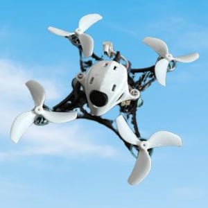 Può includere: Un piccolo drone bianco e nero con quattro eliche bianche contro un cielo blu nuvoloso. Il drone ha una fotocamera e una struttura complessa.