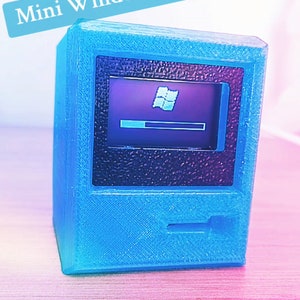 Könnte beinhalten: Ein blauer Miniaturcomputer mit einem Bildschirm, der den Windows XP-Ladebildschirm anzeigt. Der Text "Fruitiger Aereo haul" und "Mini WindowsXP computer!" sind auf dem Bild zu sehen. Ein Produkt im Retro-Stil.