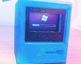 May include: A blue miniature computer with a screen showing the Windows XP loading screen. The image includes the text "Fruitiger Aereo haul" and "Mini WindowsXP computer!". This is a retro-style product.