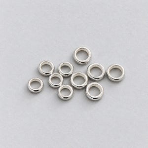 Op de afbeelding: Een verzameling van tien kleine, cirkelvormige zilverkleurige metalen ringen. Elke ring heeft een glad, afgerond oppervlak met een hol midden, gerangschikt in een losse groep. De metalen afwerking is reflecterend en uniform op alle stukken.