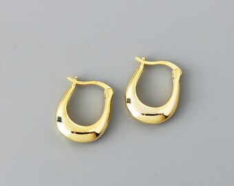May include: A pair of gold-colored hoop earrings. The earrings have a smooth, polished surface and a teardrop shape. The earrings are displayed on a gray background.