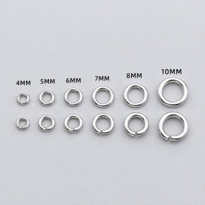 以下が含まれることがあります： 4mm、5mm、6mm、7mm、8mm、10mmとラベル付けされた6種類のサイズの銀色の金属製丸カンが2列に並んでいます。上の列は閉じられた丸カンで、下の列は切れ目のある丸カンです。