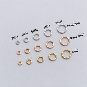 Puede incluir: Una colección de anillas de metal dispuestas en filas y columnas, etiquetadas por tamaño de 3mm a 7mm y por color como Platino, Oro rosa y Oro. Las anillas son circulares, abiertas y varían en diámetro a lo largo de las diferentes filas.
