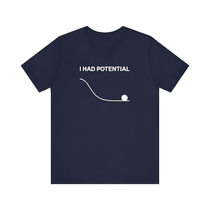 May include: Navy blue t-shirt with the text "I HAD POTENTIAL" above a white line drawing of a ball rolling down a slope. The shirt is a solid color and has short sleeves.