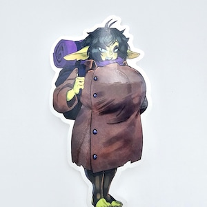 May include: A sticker featuring a cartoon goblin character with green skin, black hair, and pointed ears. The goblin wears a brown coat and carries a purple rolled-up blanket on its back. The sticker has a white border.