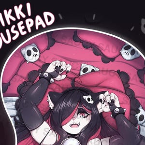 May include: A pink and black mousepad featuring a cartoon character lying on a bed of pillows. The character has long black hair, red eyes, and is wearing a black and white outfit. The mousepad has the text "NIKKI Mousepad" on it.
