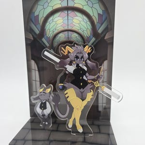 Puede incluir: Expositor acrílico de dos piezas con un personaje de anime estilizado con una espada y un personaje más pequeño. El fondo representa una vidriera y un arco de piedra. Los personajes son negros, amarillos y blancos.