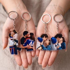 May include: Four clear acrylic keychains with silver key rings. Each keychain features a photograph of a couple kissing. Two keychains show a man in a hockey jersey. One jersey says "Graham" and the other says "44".